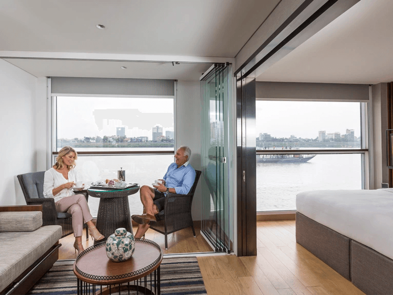 A man and woman sitting in the Scenic Sun Lounge area in the Deluxe Suite